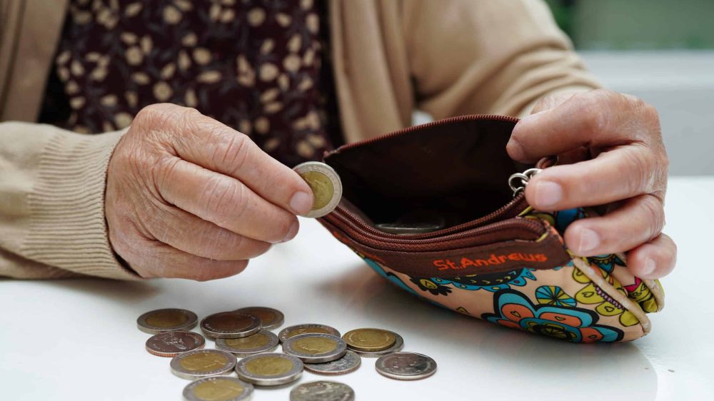 Retired elderly woman counting coins money and worry about monthly expenses and treatment fee payment.