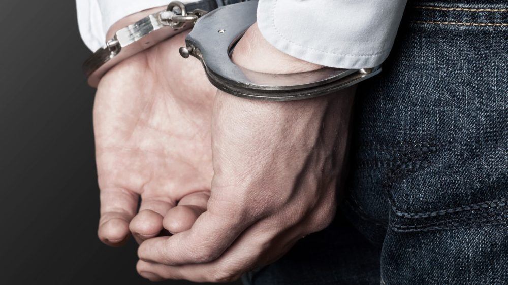 Cropped image of male hands in handcuffs behind his back